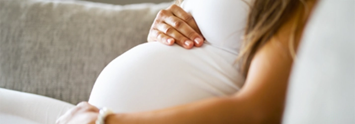 Chiropractic Stratford CT Pregnant Woman Pregnant woman sitting on a couch.